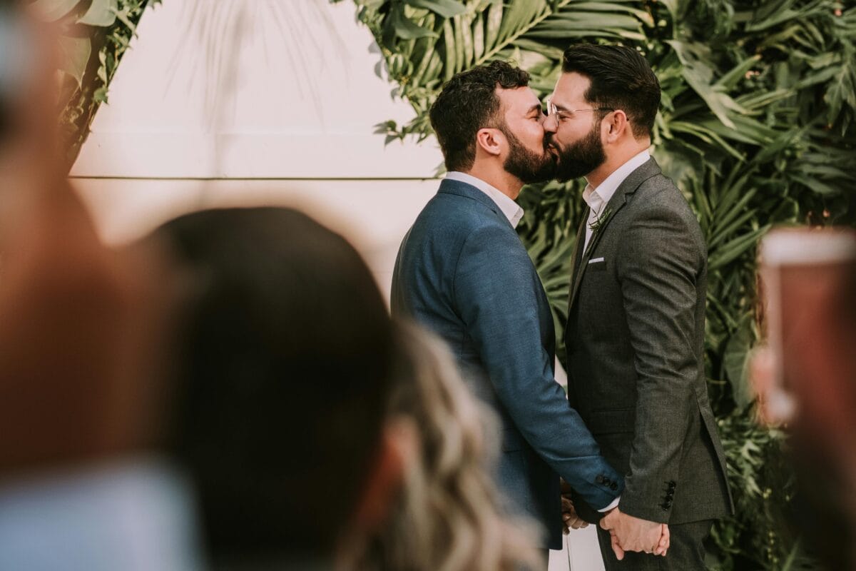 A same-sex couple shares a tender kiss at their wedding ceremony, celebrating love and commitment.